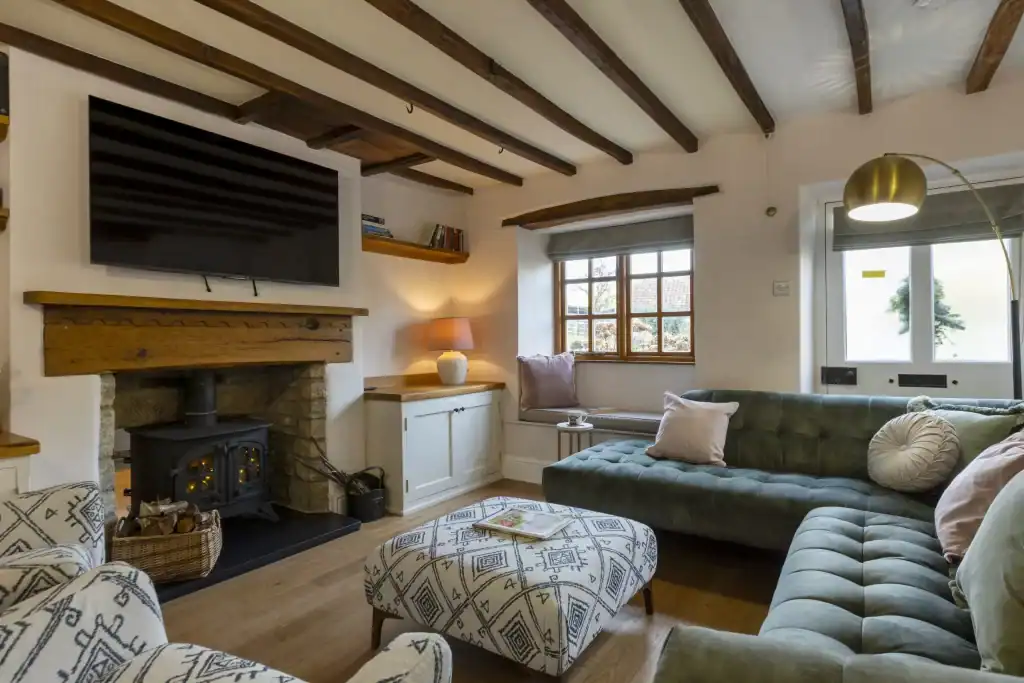 Cozy living room with exposed wooden beams and a wood-burning stove.