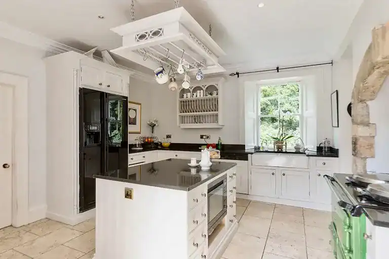 Bright Georgian villa kitchen with white cabinets and black countertops.