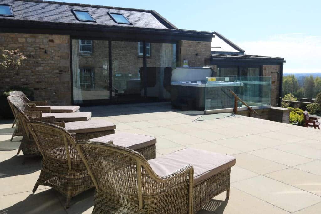 Elegant outdoor terrace with wicker chairs and glass railing at Highleases Farm.
