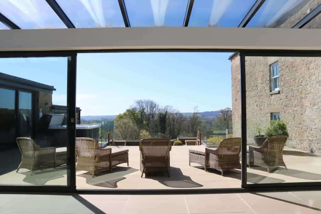 Modern sunroom with outdoor seating and scenic countryside view.