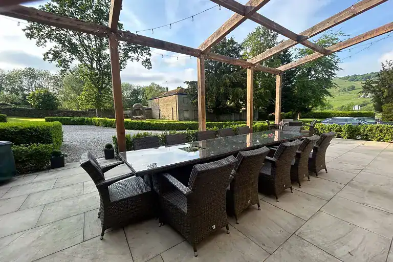 Covered outdoor dining space with a large table and wicker chairs in Pateley Bridge.