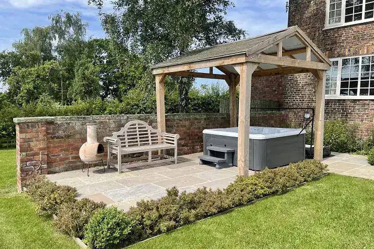 Hot tub with wooden gazebo and garden seating in Yorkshire countryside.