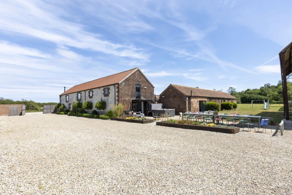 The Barn, Ganton, Yorkshire Escapes, rural stone building with outdoor seating under a blue sky.