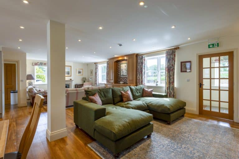 Spacious living room with green sofa and large windows in Drovers Cottage near Ripon.