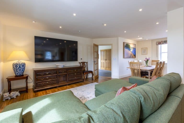 Cozy living room with green sofa, large TV, and wooden dining table near Ripon.