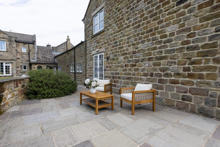 Outdoor patio with wooden furniture and stone wall at Drovers Cottage near Ripon.