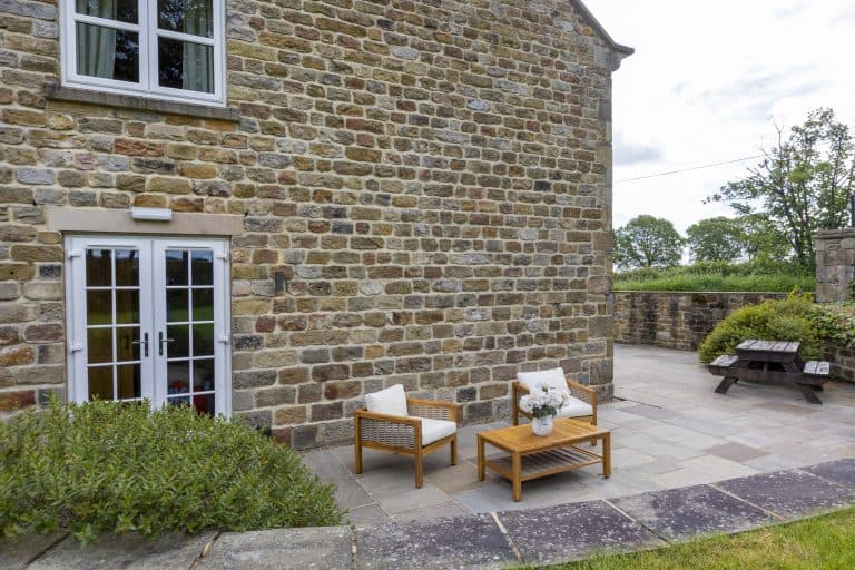 Charming stone cottage exterior with outdoor seating and garden view in Yorkshire.