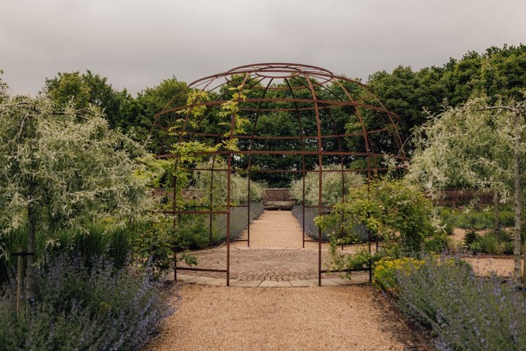Rustic garden archway with lush greenery and flowering plants in Yorkshire.