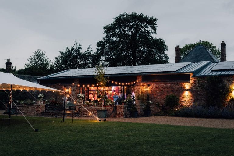 Outdoor evening event at The Stables near York with string lights and a tent.