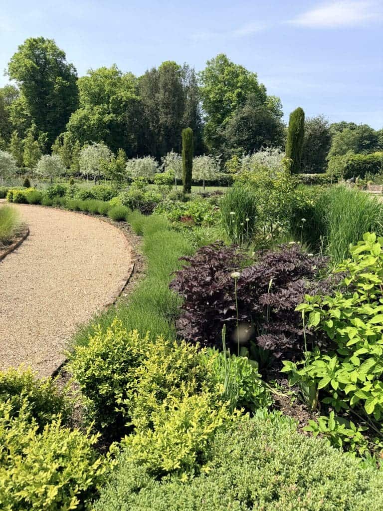 Lush garden with winding gravel path and vibrant greenery near The Stables.
