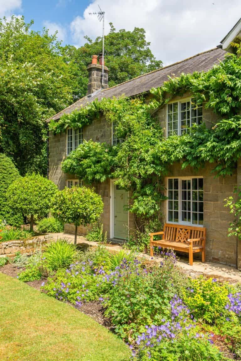 Traditional stone cottage with lush garden and wooden bench in North York Moors.
