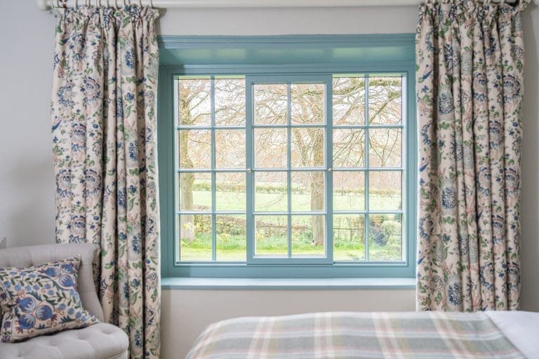 Cozy bedroom with floral curtains and a large window overlooking the Yorkshire countryside.