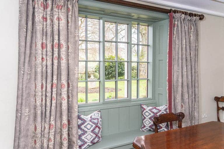 Cozy window seat with patterned cushions in a charming cottage interior.