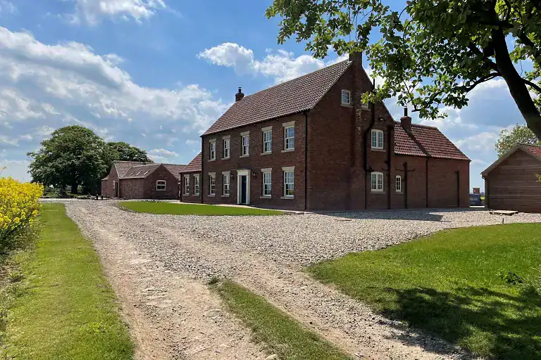 Traditional brick house with stables on Yorkshire coast under blue sky.