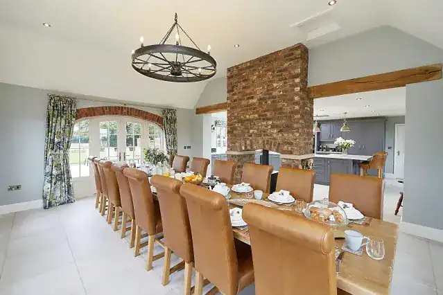 Spacious dining room with large table, leather chairs, and brick feature wall.
