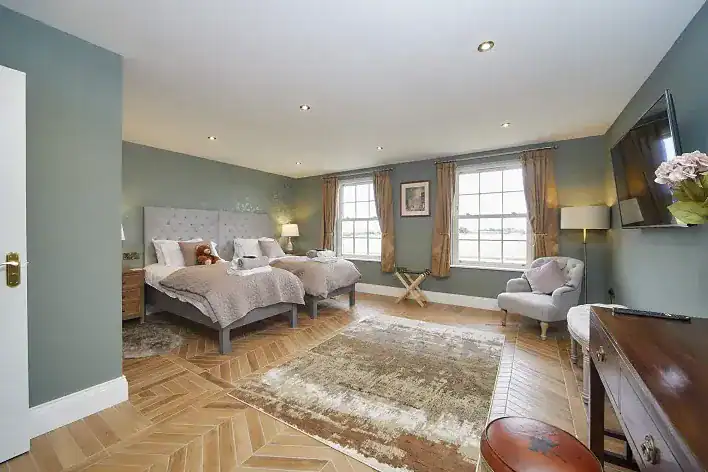 Spacious bedroom with two beds, large windows, and elegant decor in Yorkshire Coast.
