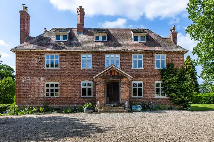 Historic brick house with multiple chimneys and a gravel driveway in Yorkshire.