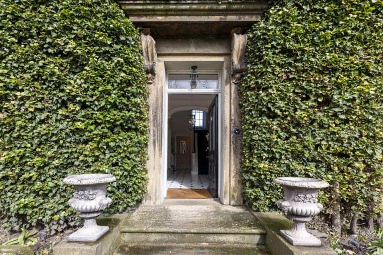 Historic entrance to Granby House in Harrogate with lush greenery and stone planters.