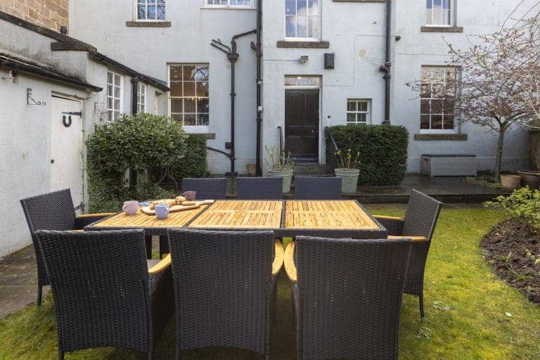 Outdoor dining area with a table and six chairs in a garden at Granby House, Harrogate.