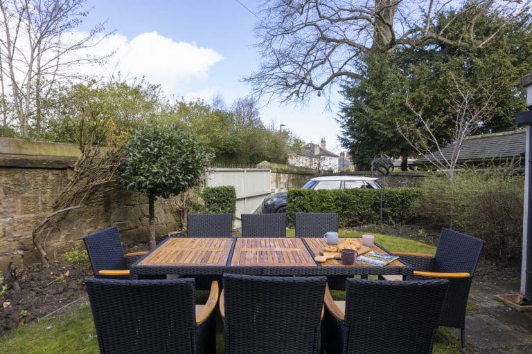 Outdoor garden dining area with a wooden table and six black chairs in Harrogate.