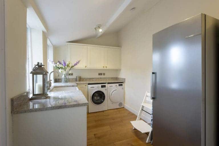 Modern laundry room with washing machine, dryer, and fridge in Yorkshire home.