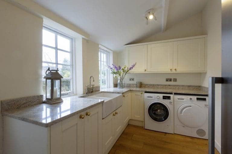 Bright kitchen with white cabinets, granite countertops, and washing machine in Harrogate.