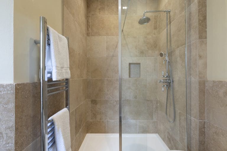 Modern walk-in shower with beige tiles and glass partition in Yorkshire Escapes bathroom.