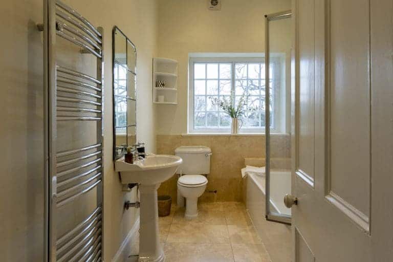 Bright, modern bathroom with bathtub, shower, and large window in Yorkshire home.