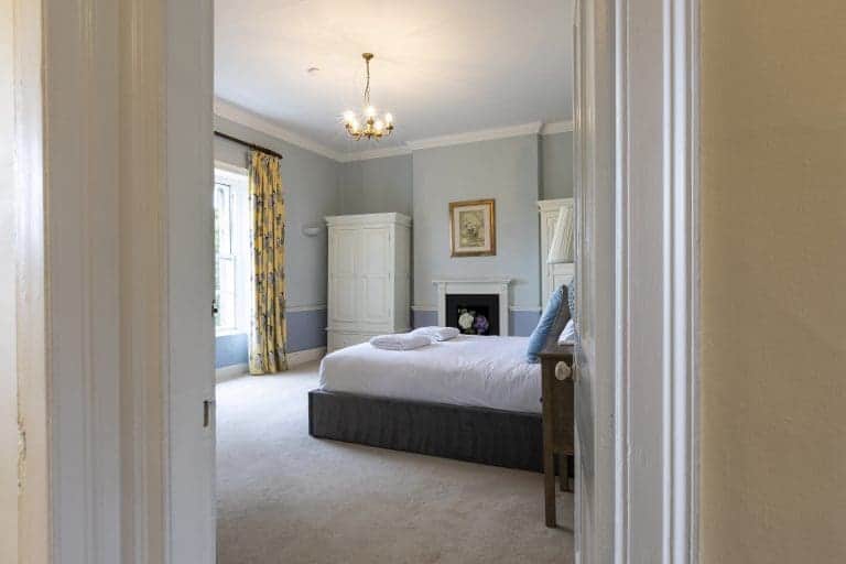 Elegant bedroom with a large bed, white wardrobe, and vintage decor in Harrogate.