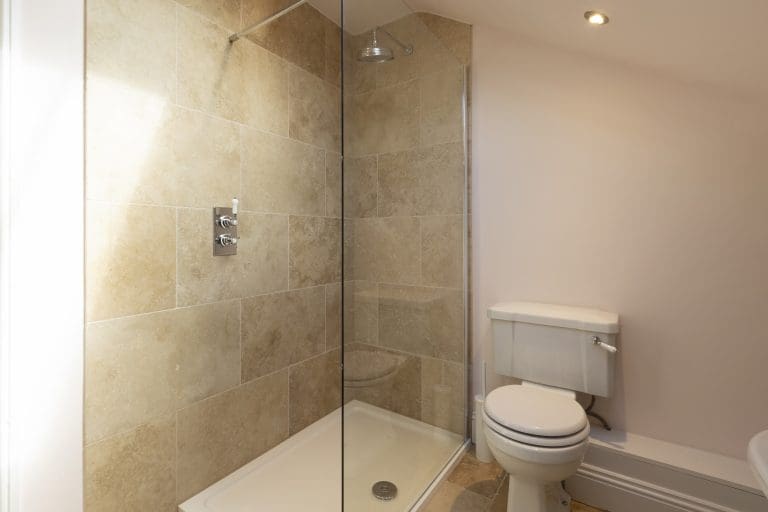Modern walk-in shower with beige tiles in Yorkshire Escapes property.
