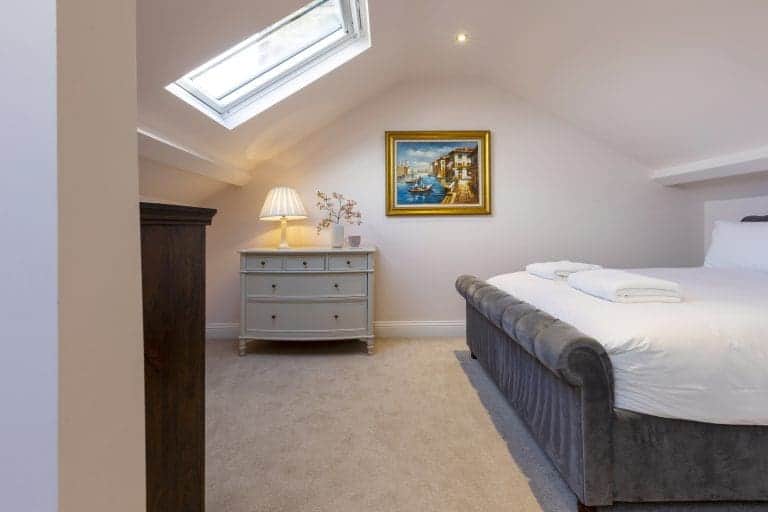 Cozy bedroom with skylight, white walls, and elegant furniture in Granby House, Harrogate.