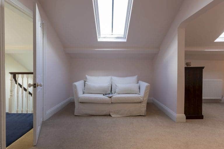 Bright attic room with a white sofa under a skylight window.