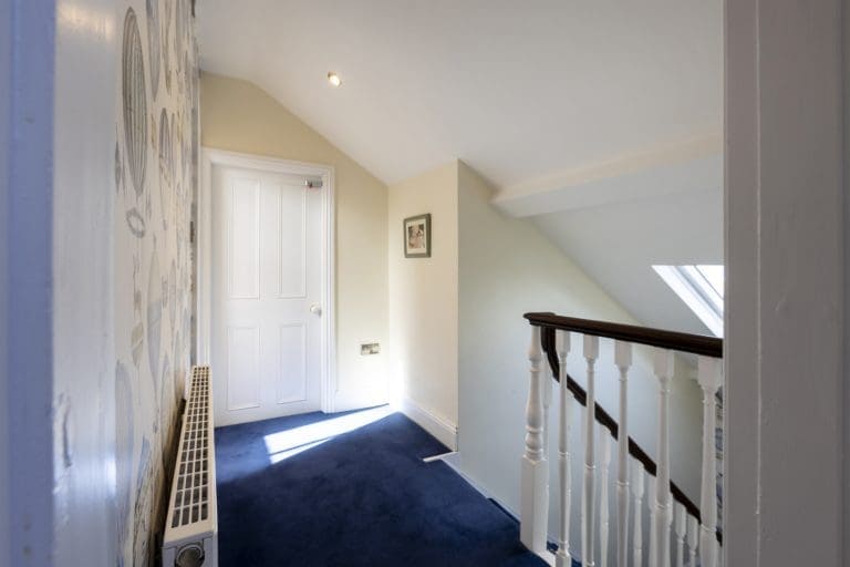 Bright hallway with white walls, blue carpet, and staircase in Yorkshire Escapes property.