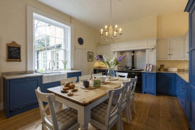 Bright kitchen with blue and white cabinets and a wooden dining table.