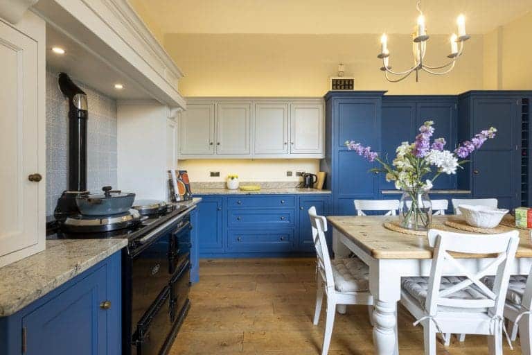 Modern kitchen with blue cabinets and white dining table in Yorkshire Escapes.