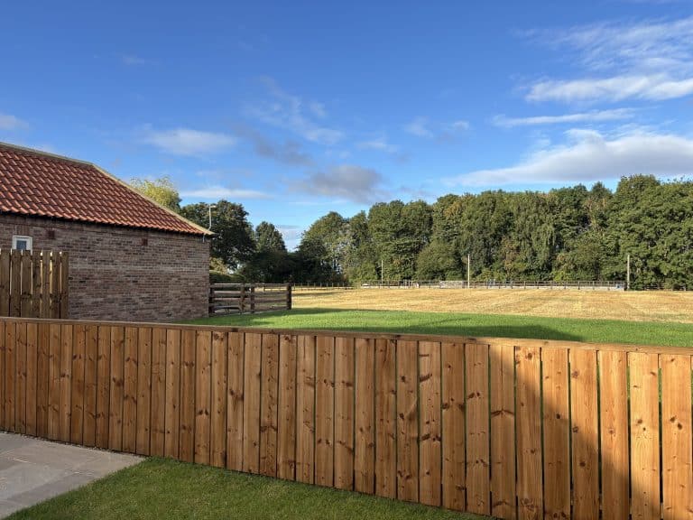Scenic view of countryside with wooden fence and trees near Haget Barn.