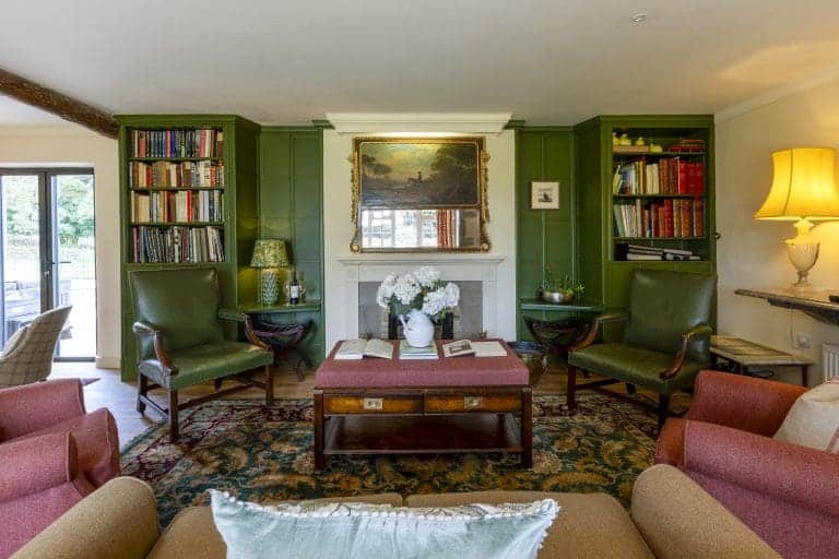 Cozy living room with green walls, bookshelves, and comfortable armchairs.