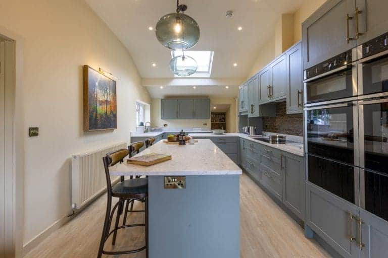 Modern kitchen with blue cabinets and marble island in Yorkshire Dales holiday home.