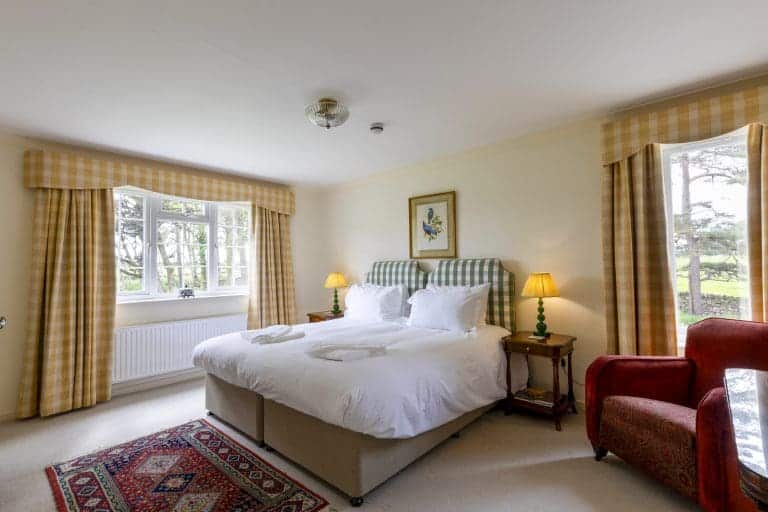 Cozy bedroom with large bed, yellow check curtains, and countryside views.