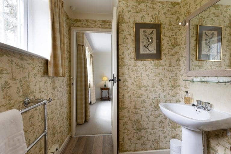 Cozy bathroom with vintage wallpaper and a white sink in Yorkshire Dales cottage.