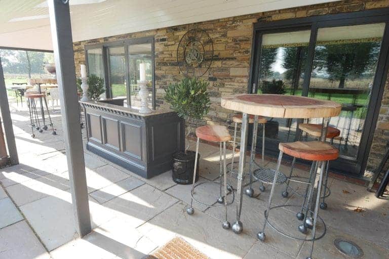 Outdoor patio with bar table, chairs, and stone wall at Cedar House, East Yorkshire.