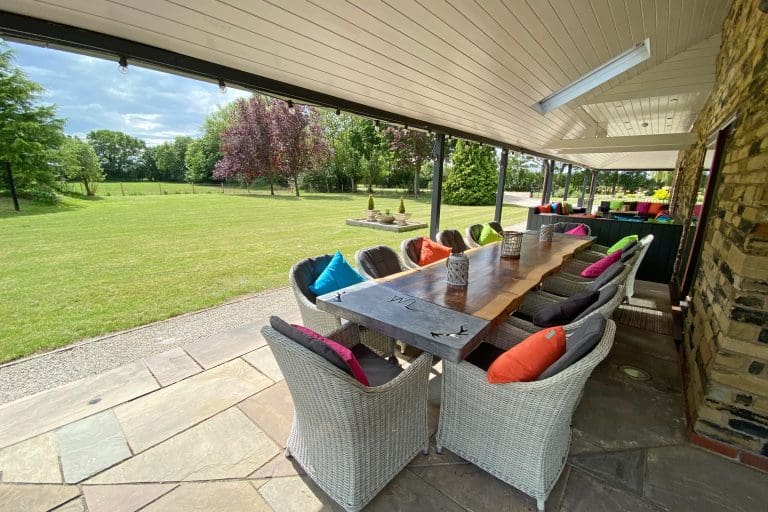Outdoor dining area at Cedar House, East Yorkshire with colourful cushions and scenic garden view.