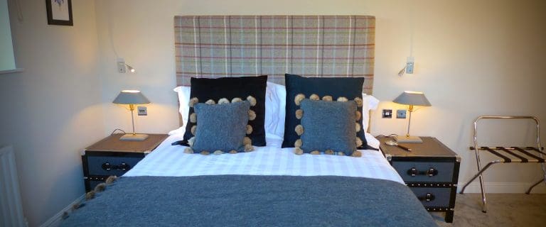 Cozy bedroom with plaid headboard and decorative cushions in Cedar House, East Yorkshire.
