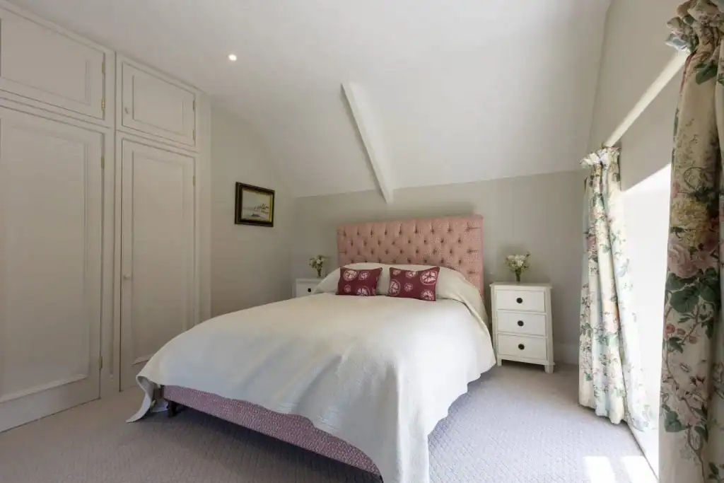 Cozy bedroom with pink headboard and white bedding in Yorkshire escape.