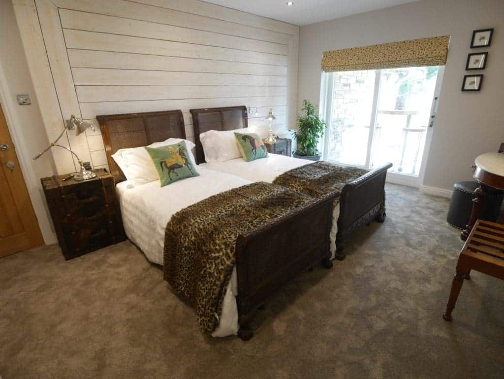 Comfortable bedroom with wooden bed, animal-themed cushions, and natural light from balcony.