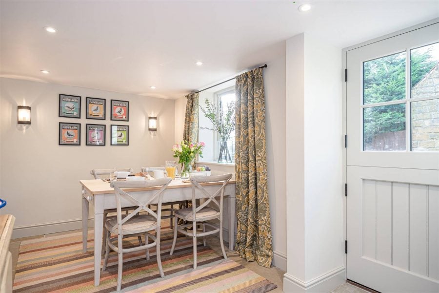 Bright dining area with a white table, chairs, and colourful artwork in Yorkshire holiday home.