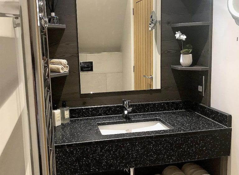 Contemporary bathroom sink with black speckled countertop and mirror.