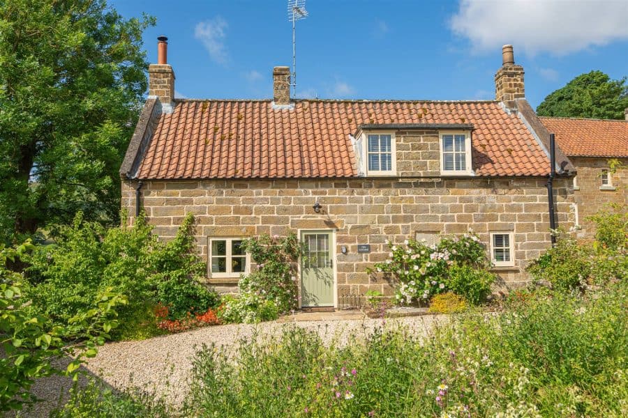 Charming stone cottage with red-tiled roof in Yorkshire countryside.