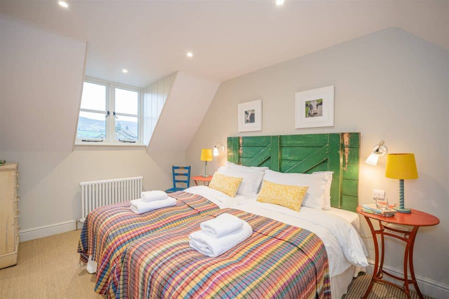 Cozy bedroom with colourful plaid bedding and green headboard in Yorkshire escape.