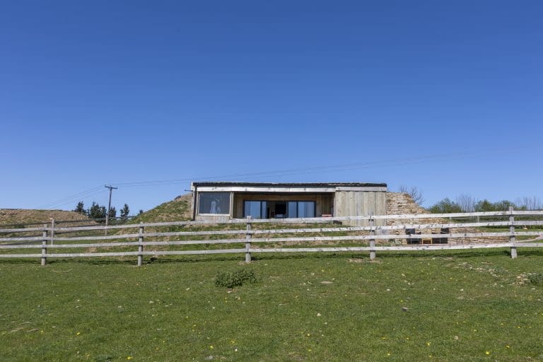 Modern building on a grassy hill with a clear blue sky.